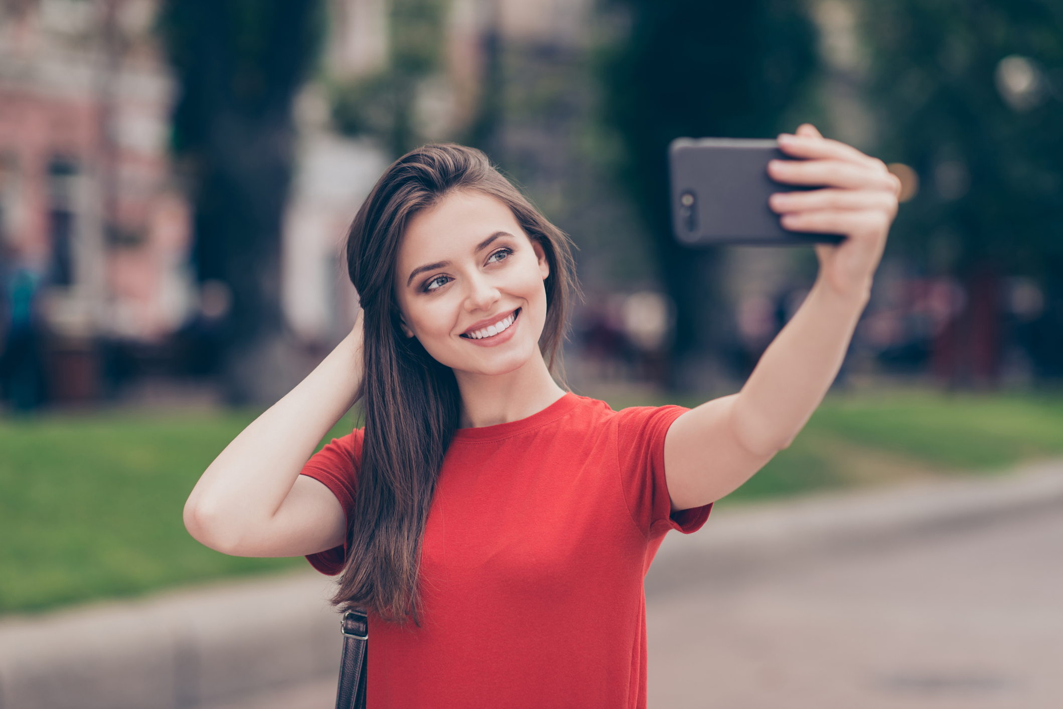 Девушка улыбается с телефоном на улице